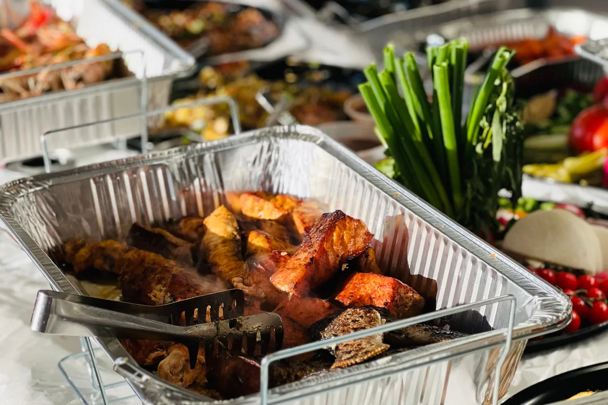A catering buffet spread of roasted meats and vegetables, representative of a hangi-style dinner